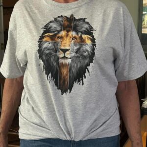 Light gray t-shirt featuring a realistic lion graphic in grayscale with a cross overlay. Available sizes: S-L Women's Cut